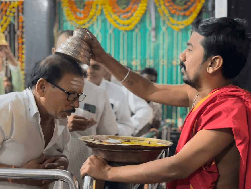 Priest offering prasadam to a devotee at Sri Maha Panchamukheswara Swamy Vari Devasthanam